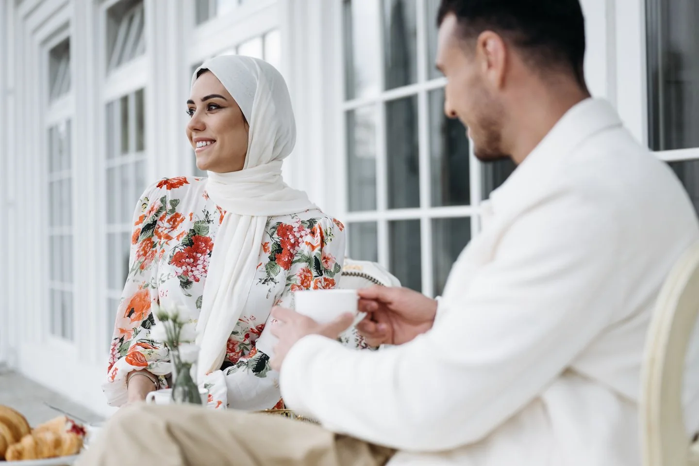 Dos adultos conversan mientras toman café al aire libre