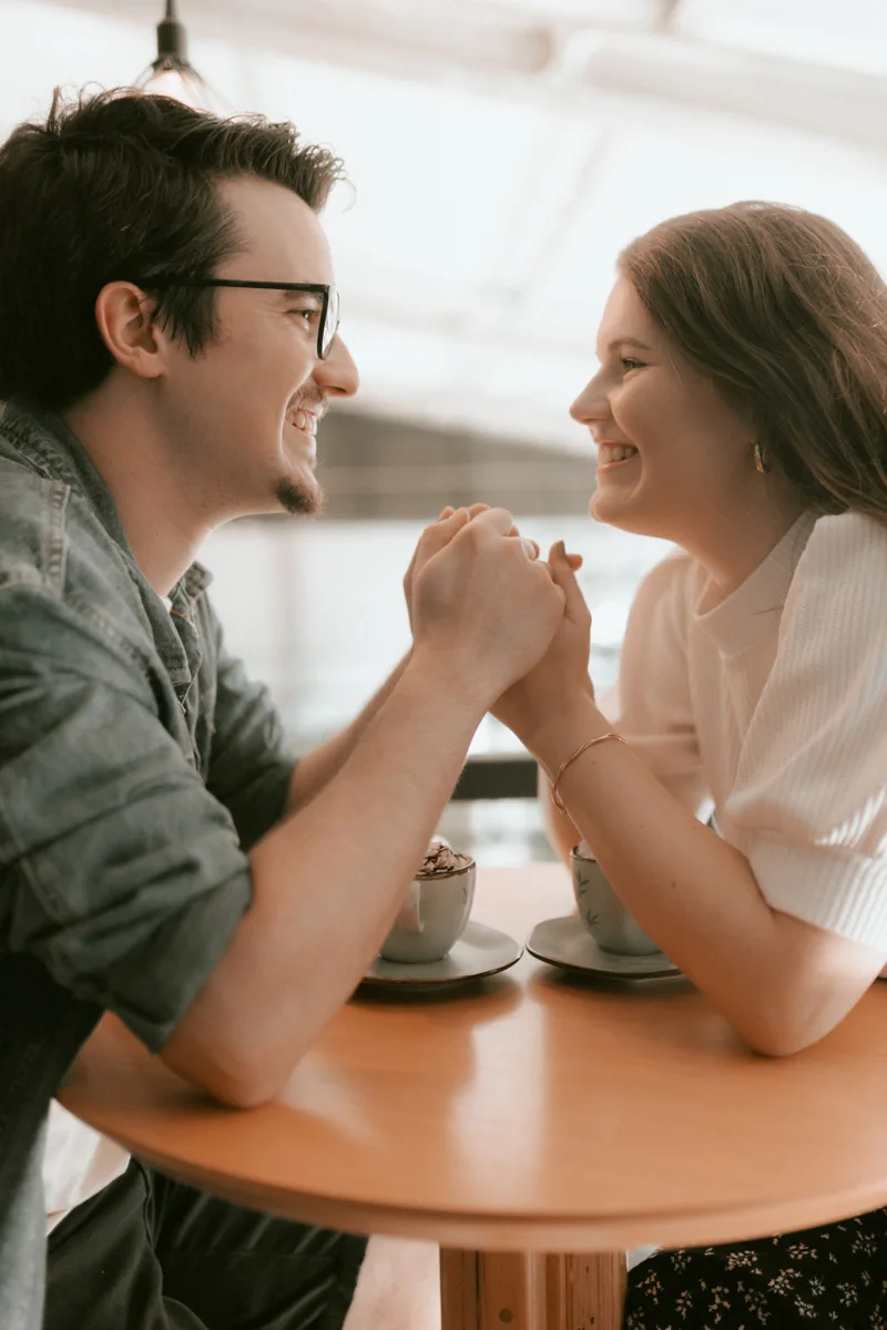 Dos adultos comparten un café y sonríen en una mesa